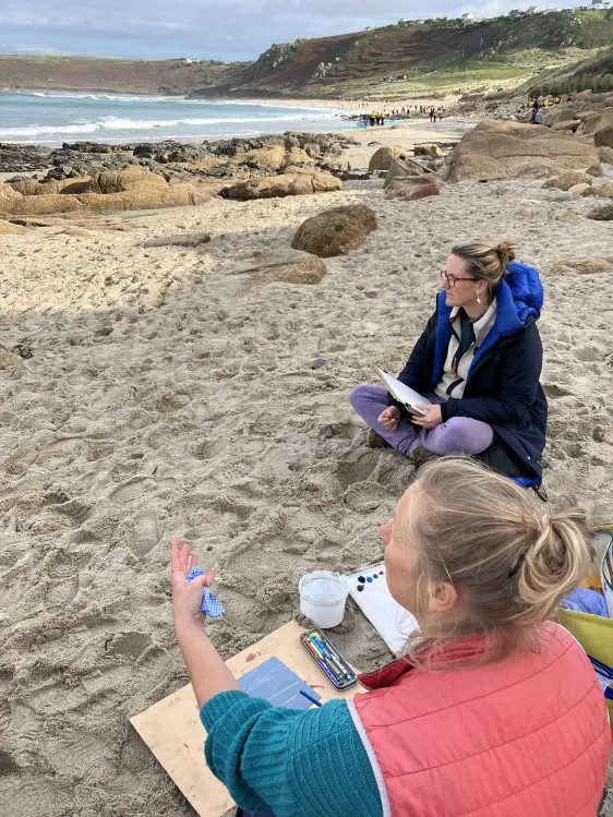 2 artists sat on the beach discussing the landscape